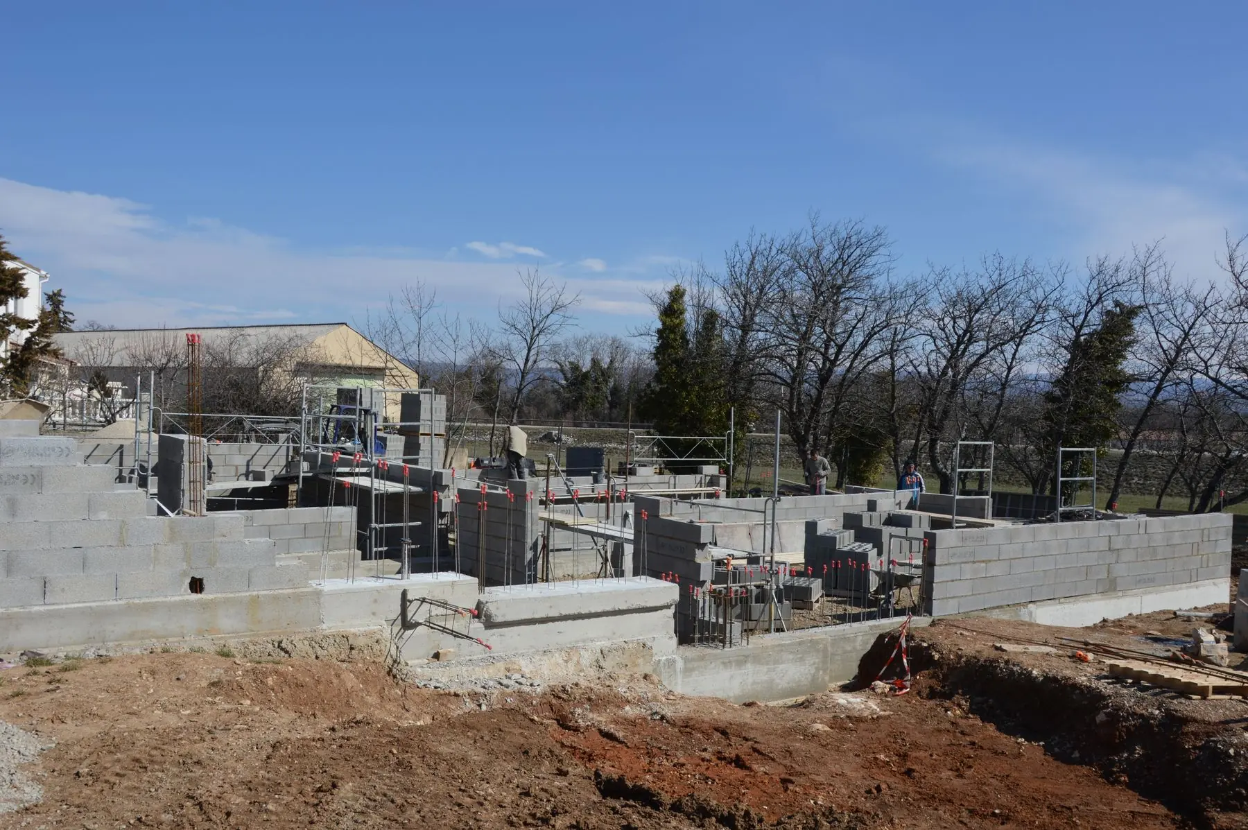 Chantier de construction : murs en parpaing et échafaudages sous un ciel dégagé