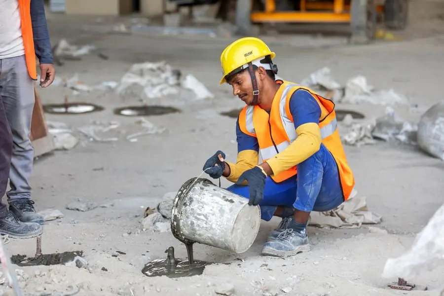 Ouvrier coulant et égalisant une dalle de béton frais